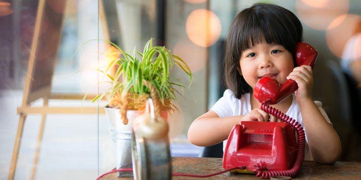 child using a traditional rotary dial home phone