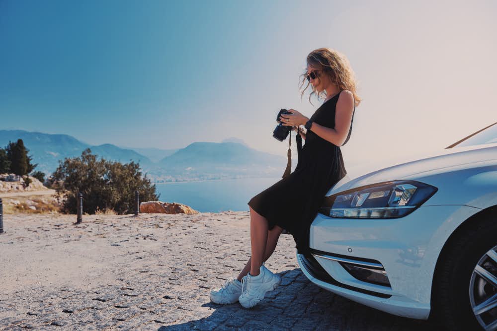 Woman professional photographer standing with dslr camera near her car while travel in Turkey