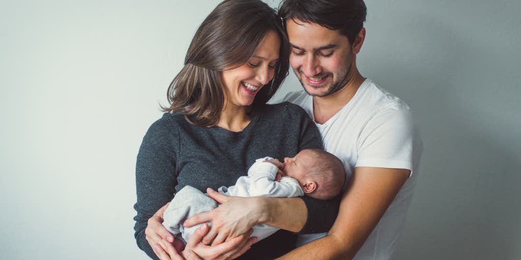 Portrait of young smiling family with newborn 