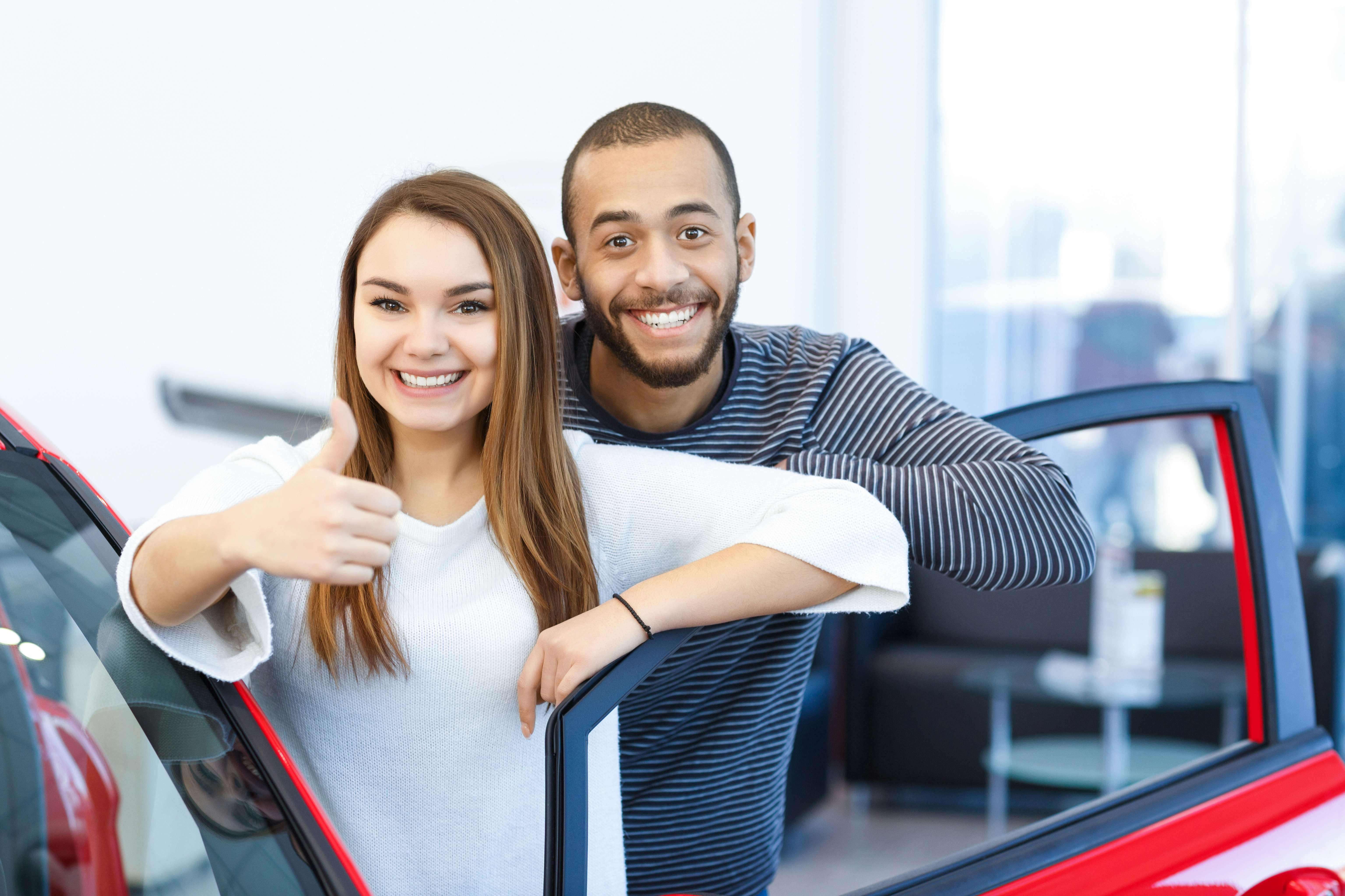 Couple checking out a new car at the dealership looking into vehicle at the salon international interracial buying car relationship concept N