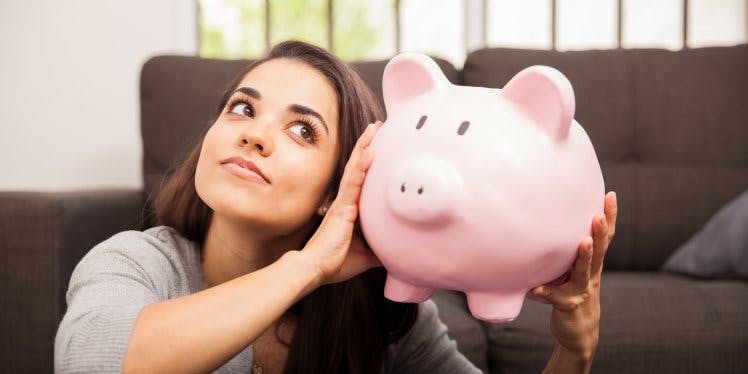 woman-holding-piggy-bank-in-living-room