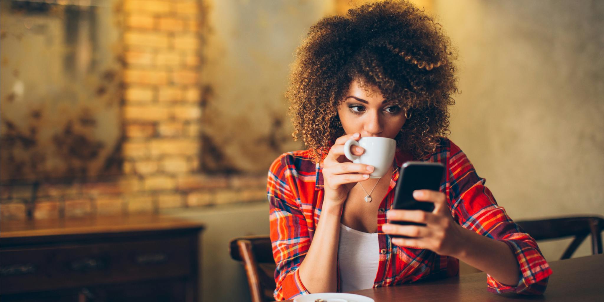 Lady drinking coffee and using smartphone