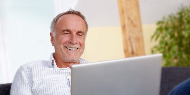 older man on sofa with laptop