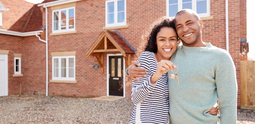 Image of man and woman holding keys to new home