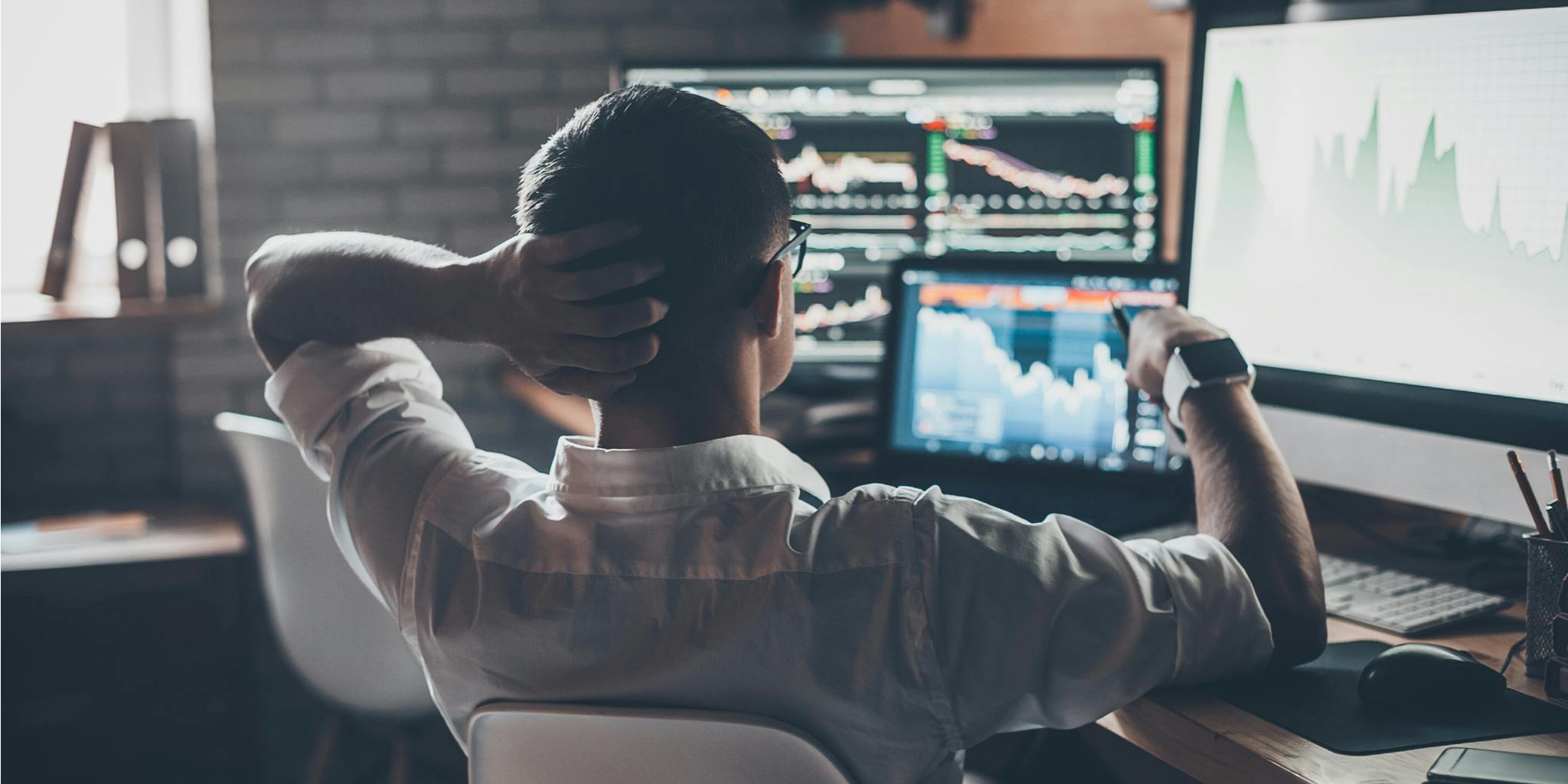 Man looking at the stock market on multiple screens