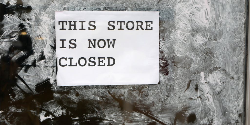 'this store is now closed' sign on door sprayed with white paint illustrating economic down turn on British high street