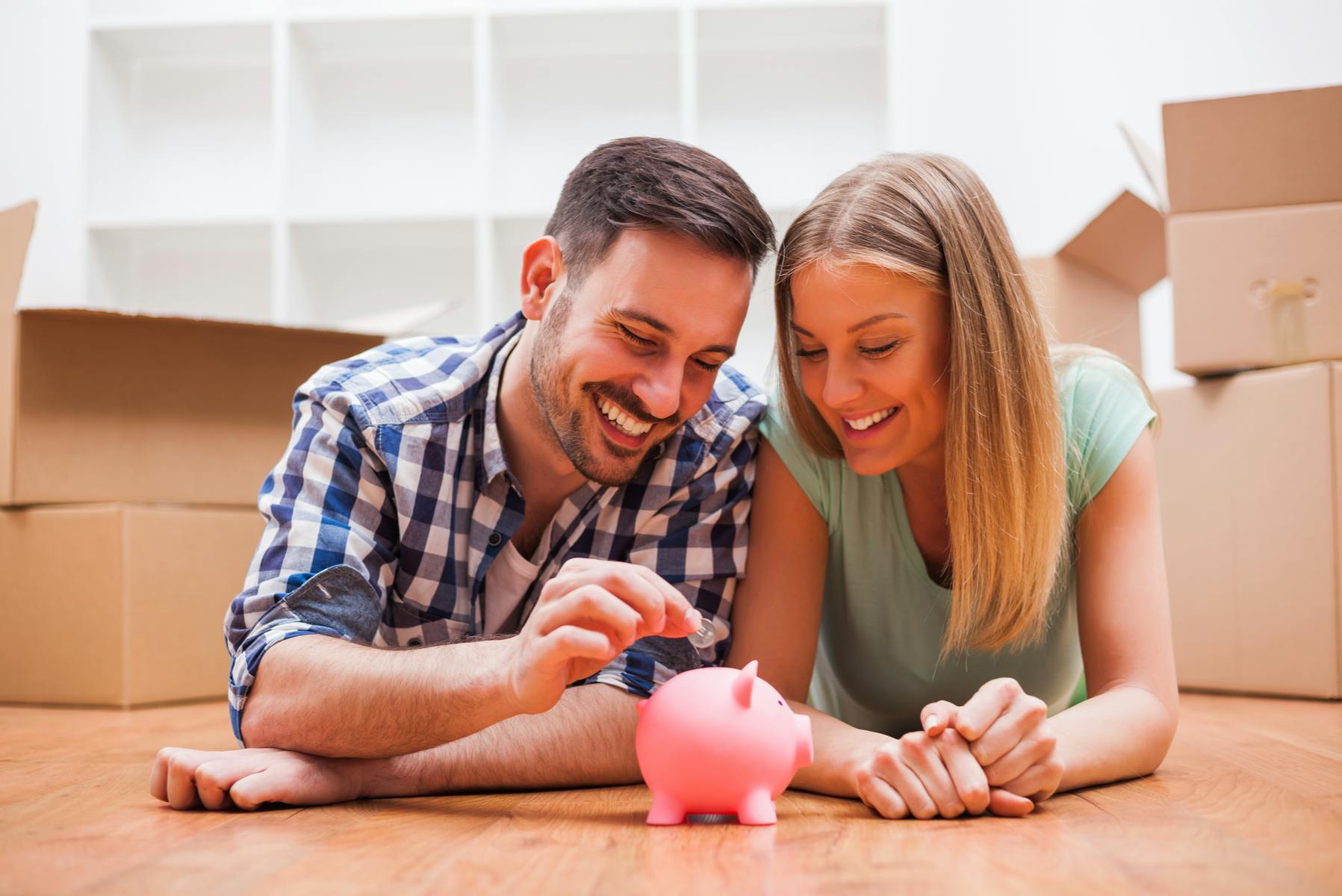 Man and woman lying on floor with a piggy bank