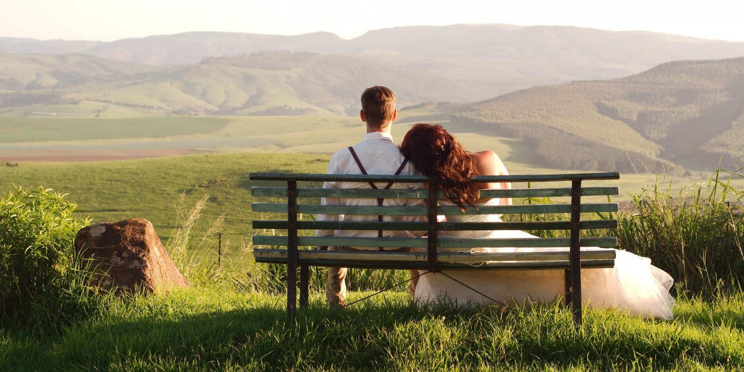 Newlywed couple sitting on park bench