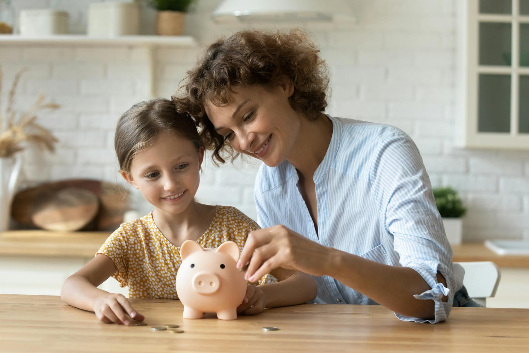 Mother and daughter and money to a piggy bank