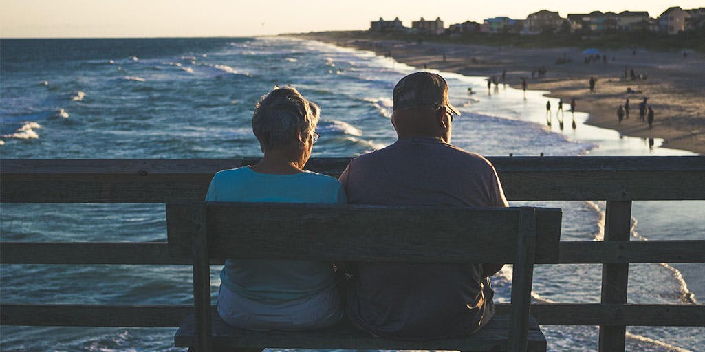 Elderly couple on a bench looking out to sea 