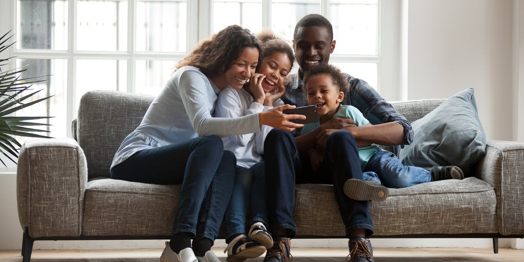 happy family on a sofa looking at a mobile device