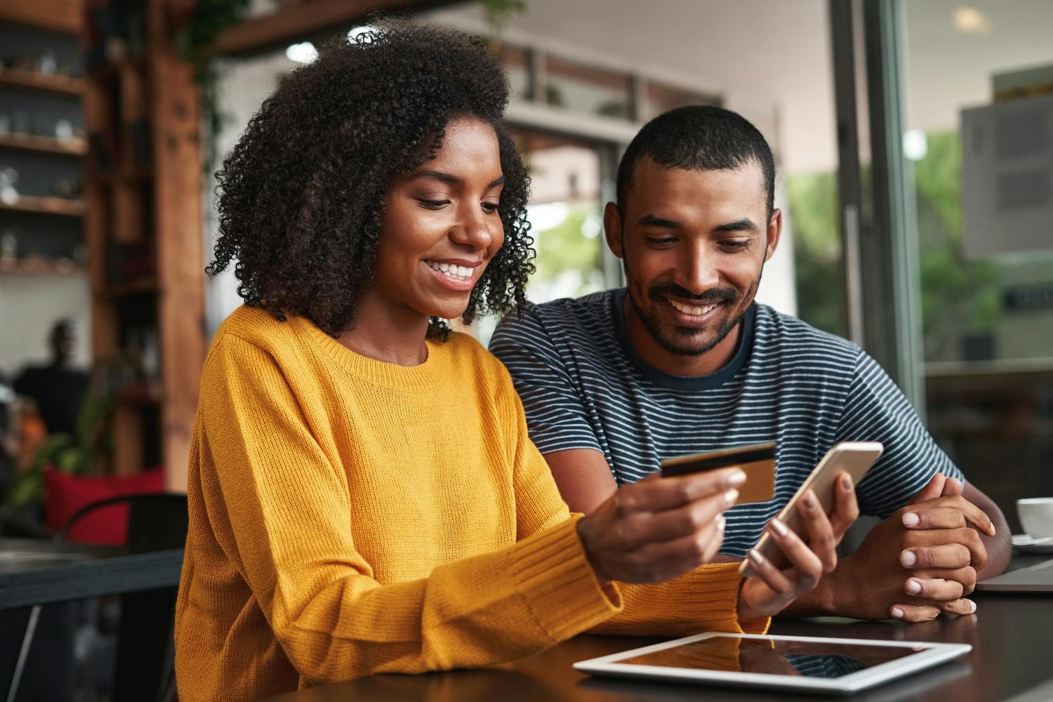 Black woman with boyfriend using credit card to shop online 