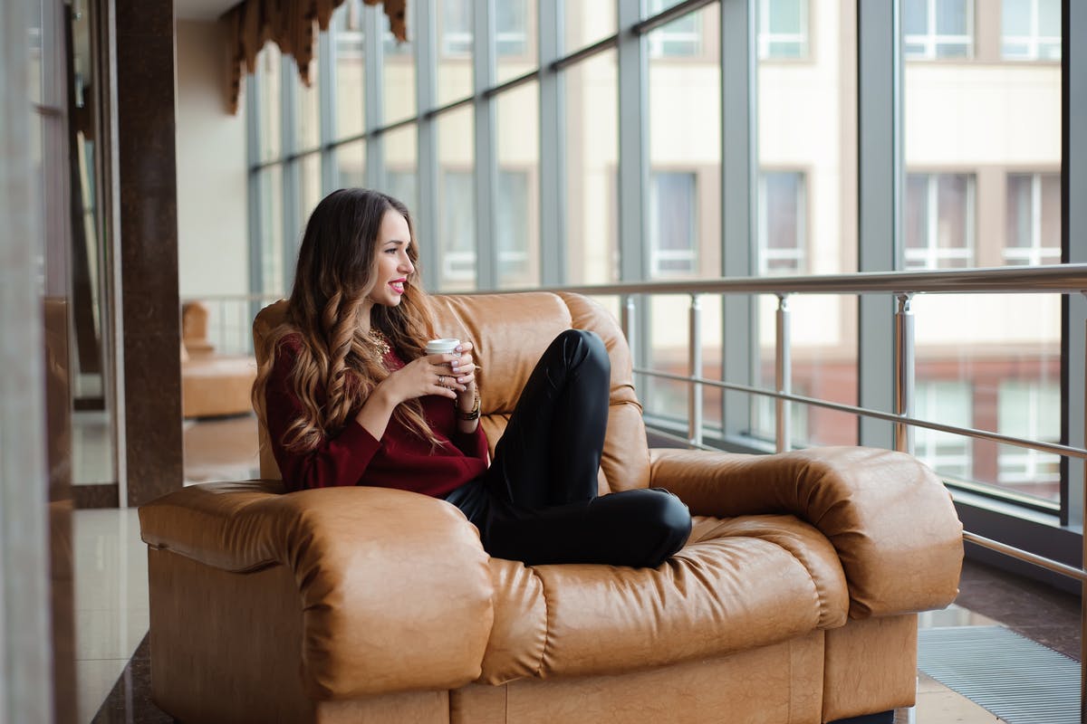 A woman relaxes with a cup of coffee in an airport comfortable lounge chair