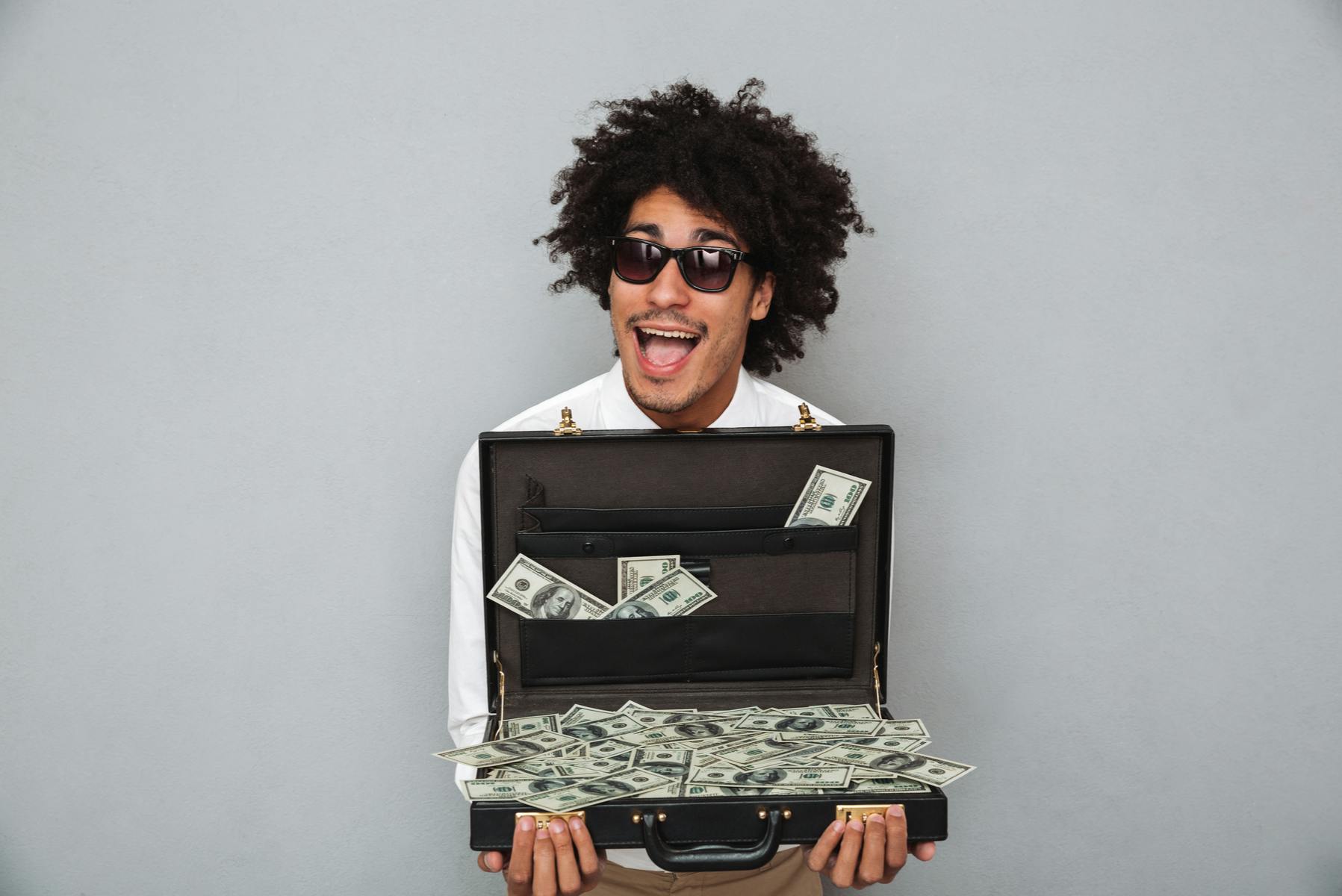 Man holding an open suitcase full of money