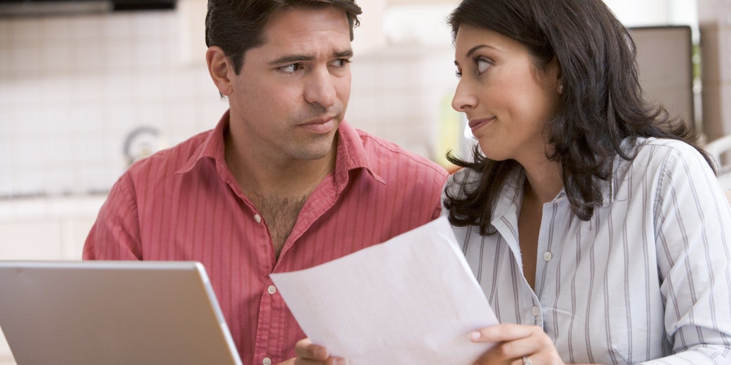Concerned couple at home with bills and laptop